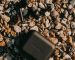 From above of black true wireless earbuds and battery case on dry rocky surface